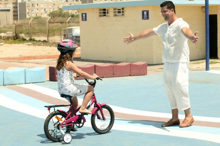 Trainer helping kid to learn bike riding © Depositphotos