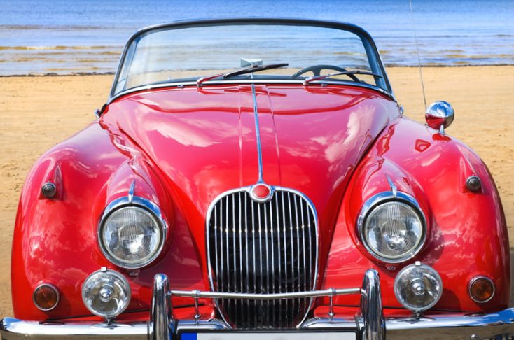 Old classic red car at the beach © Depositphotos