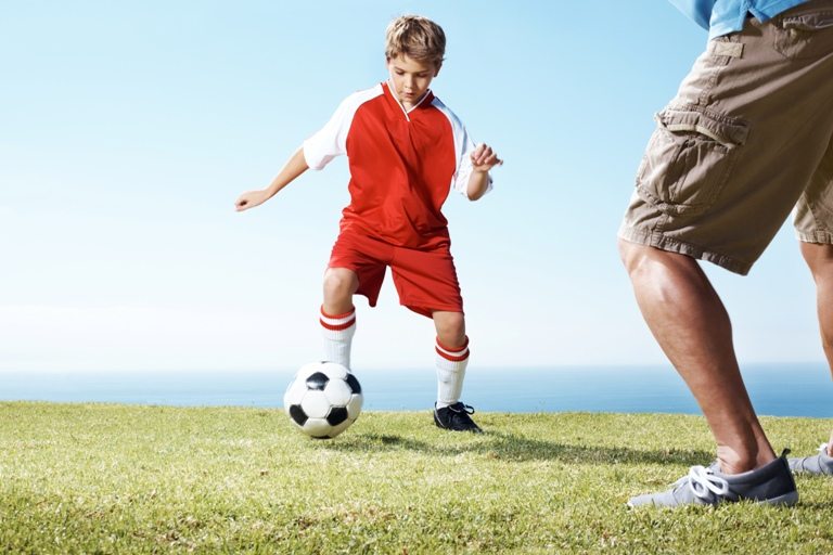 Small boy playing a soccer game with a man © Depositphotos