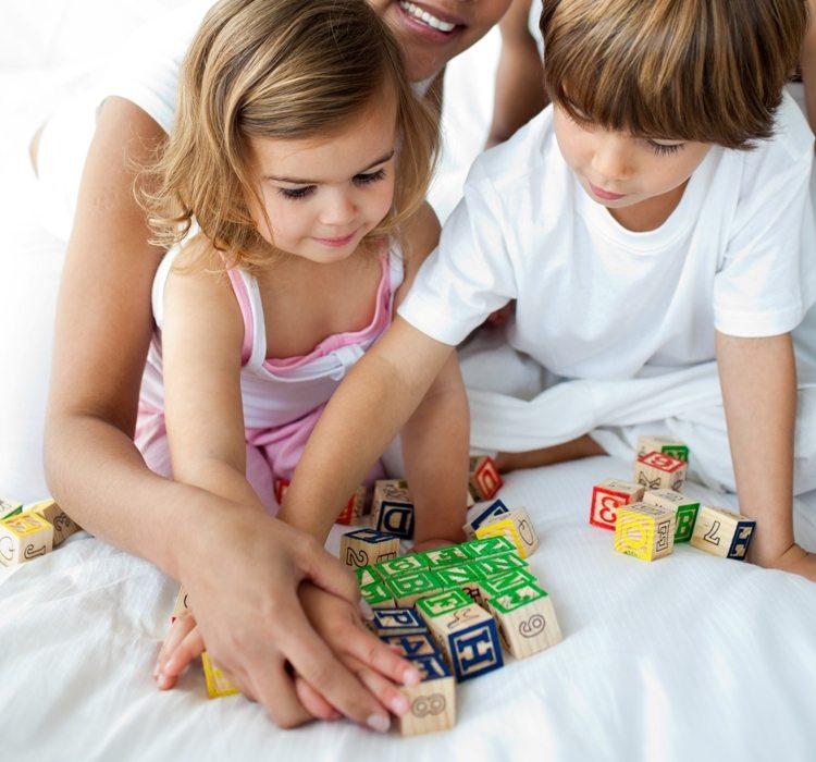 Close-up of brother and sister playing with cube toys © Depositphotos