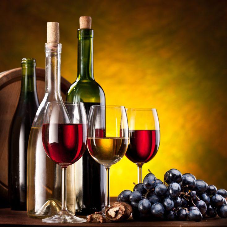 Still life with wine bottles, glasses and oak barrels.