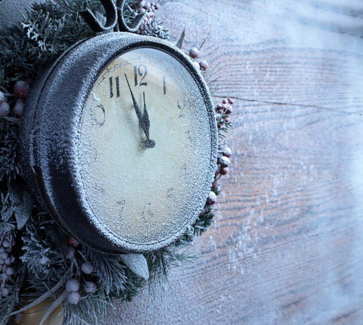 Christmas clock over snow wooden background.