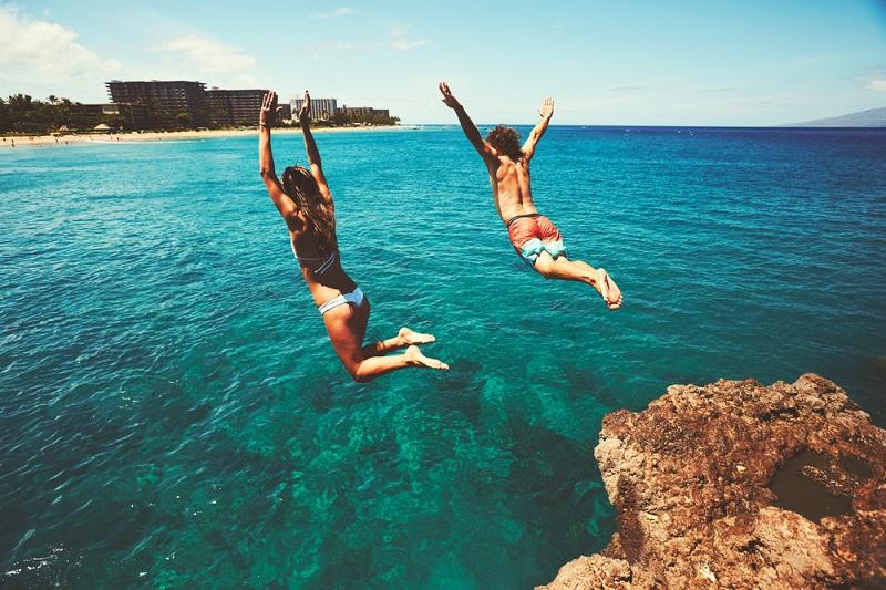 Friends cliff jumping into the ocean