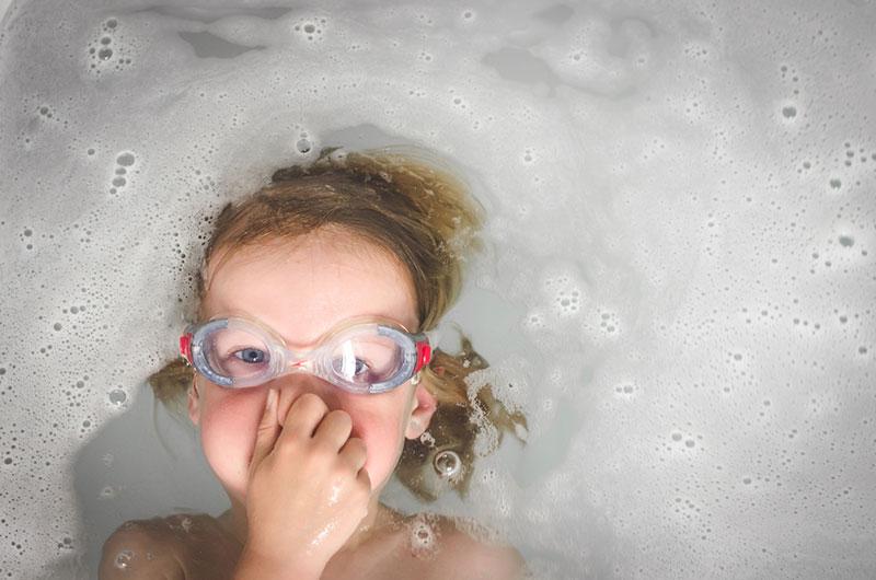 Boy with goggles playing in bathtub