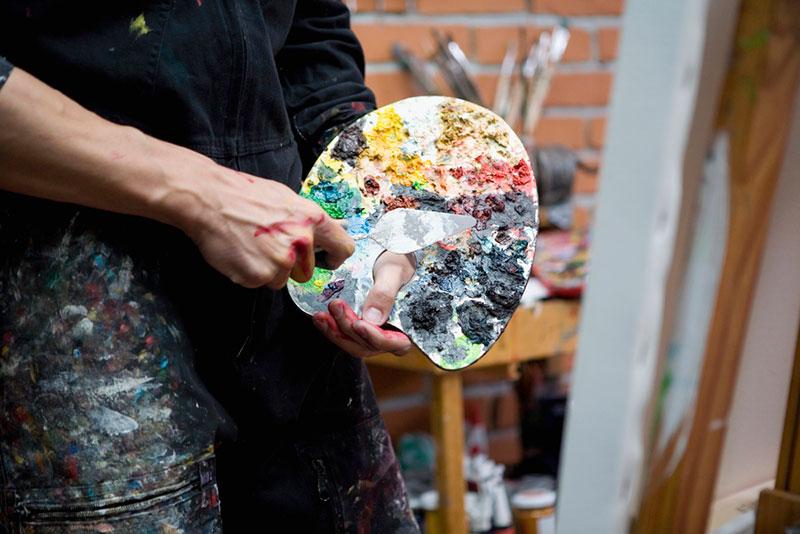 Midsection of artist holding palette and painting knife