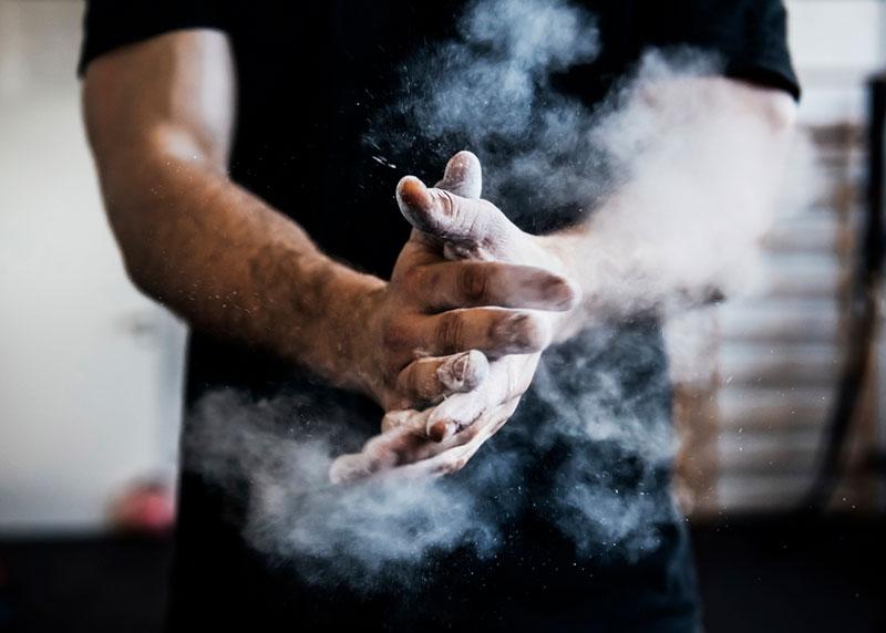 Man chalking hands in gym, close up