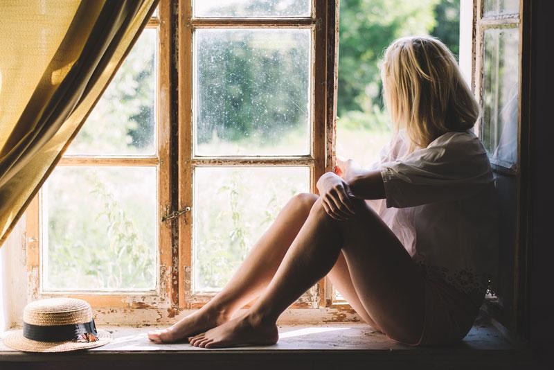 László Lőrik photography - woman sitting on a windowsill 