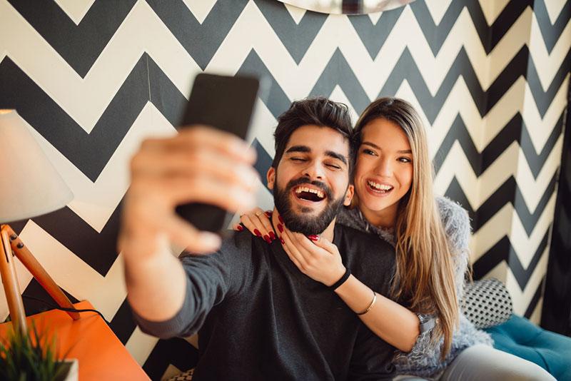 Nebojsa Tatomirov stock photography - Young man with beard taking selfie with girlfriend while sitting in cafe