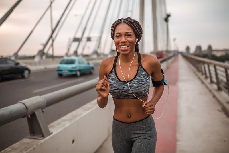 Nebojsa Tatomirov stock photography - Fit african american woman running while listening to music through earphones