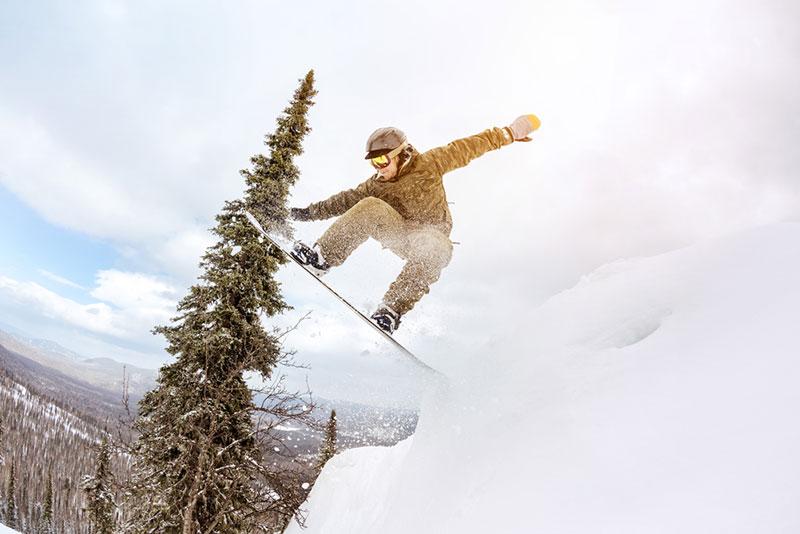 Snowboarder jump offpiste forest freeride