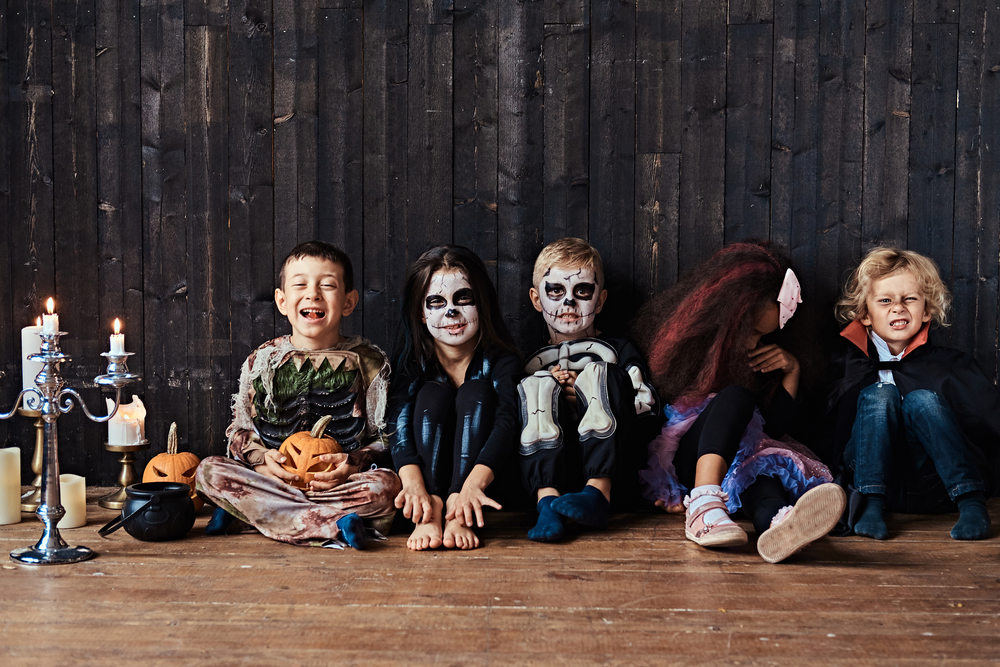 Halloween party with group children who sitting together on a wooden floor in an old house. Halloween concept.