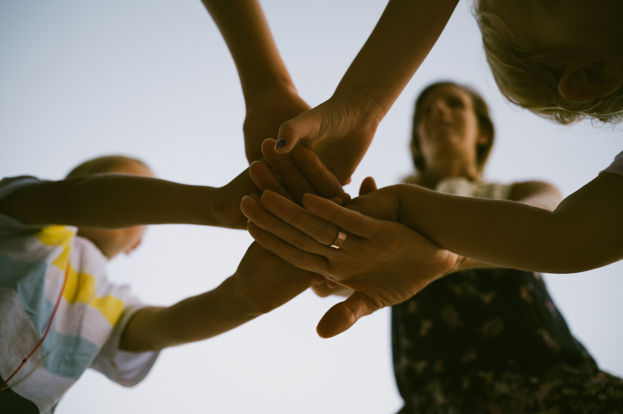 View from below of a mother and five kids stacking their hands