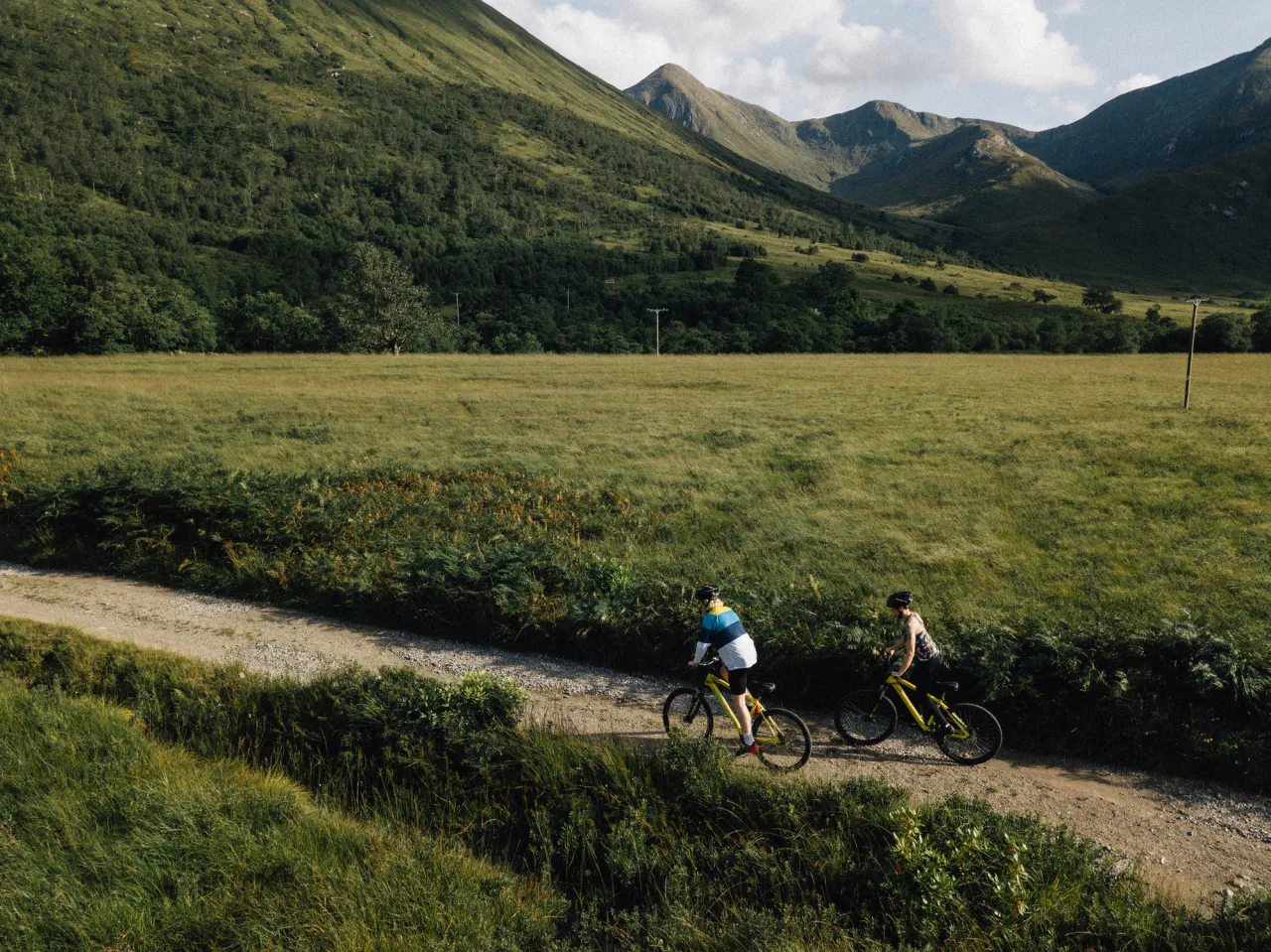 Couple cycling down a road in the Scottish Highlands