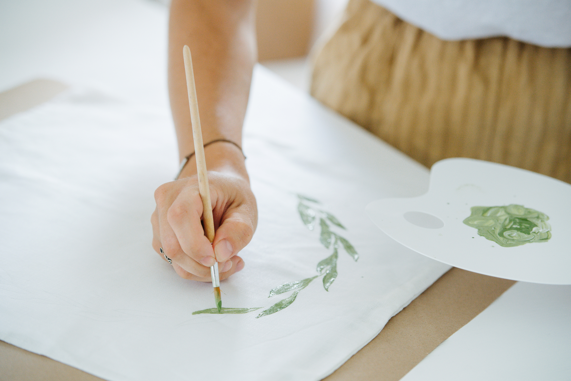 close-up hands paint a floral ornament