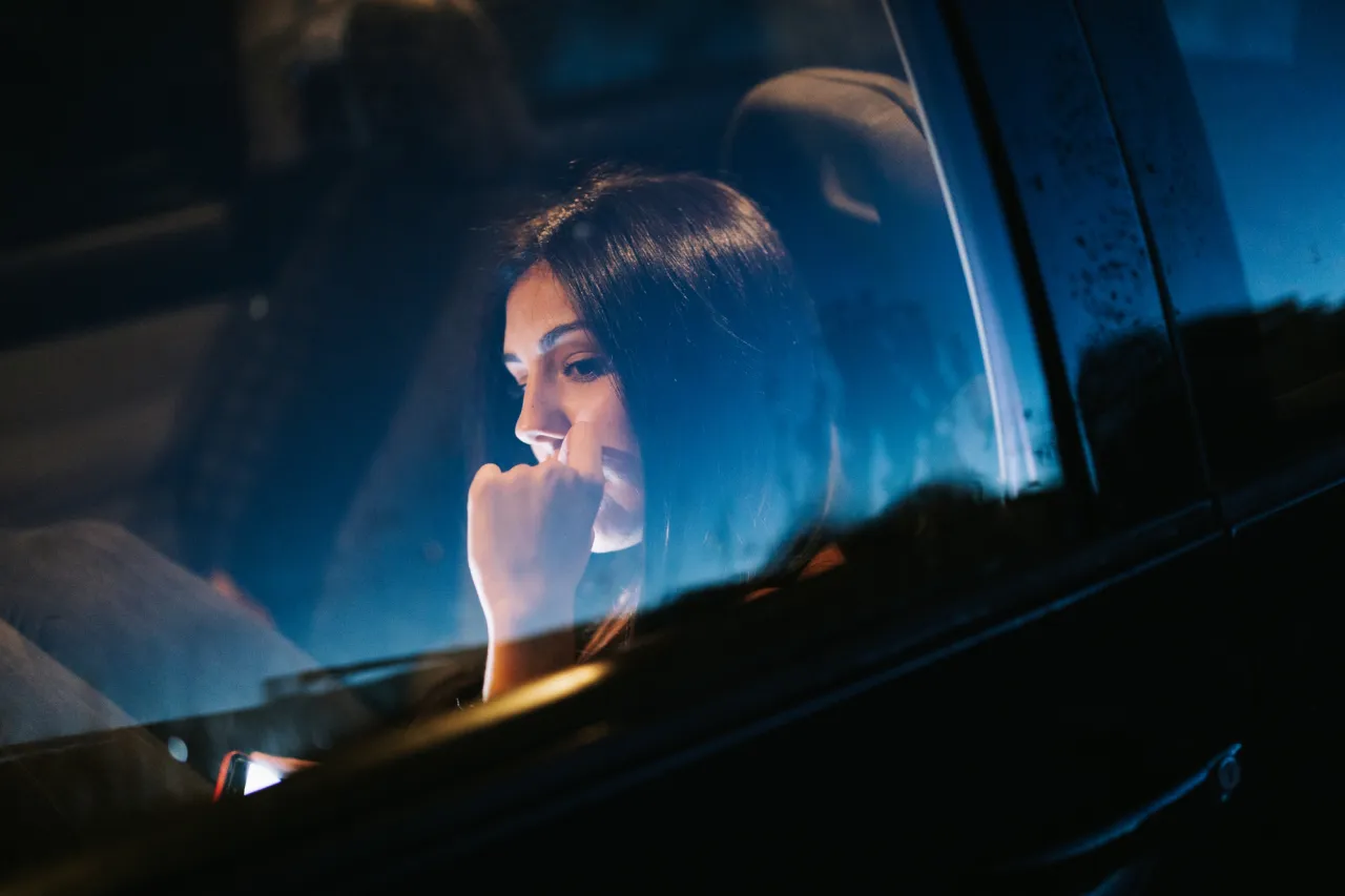 stock photo Young woman inside a car using her smartphone