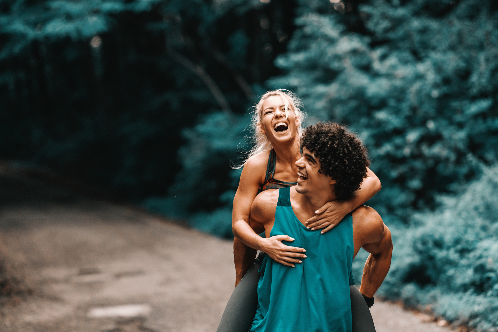 Happy sporty Caucasian couple having piggyback in nature in summertime stock photography