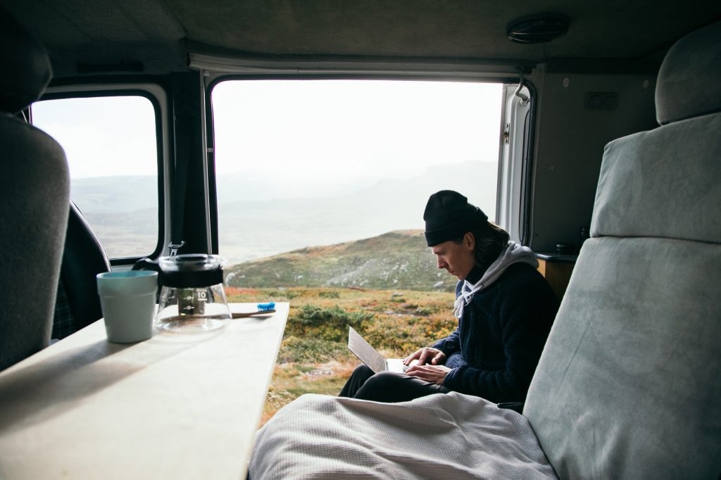 Jovem trabalhar no laptop de van campista no acampamento