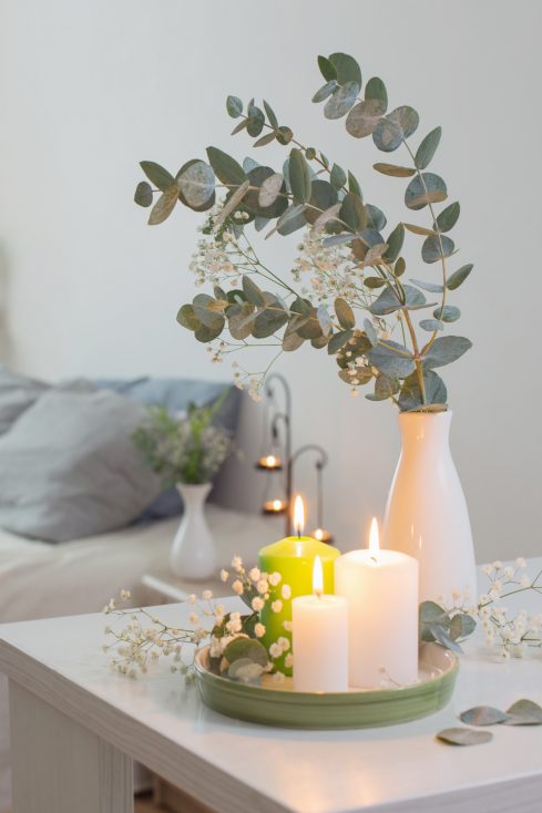 Queimando velas e eucalipto em vaso no quarto branco