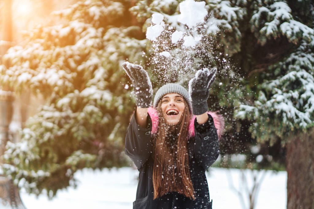 A menina joga neve na cidade