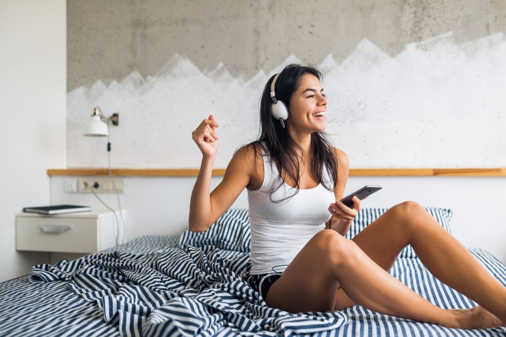 Mulher sorridente muito sentado na cama de manhã