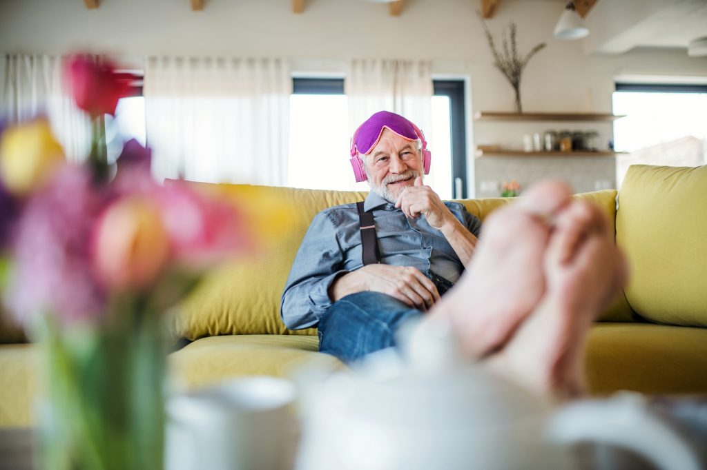 Um homem sênior com fones de ouvido e máscara