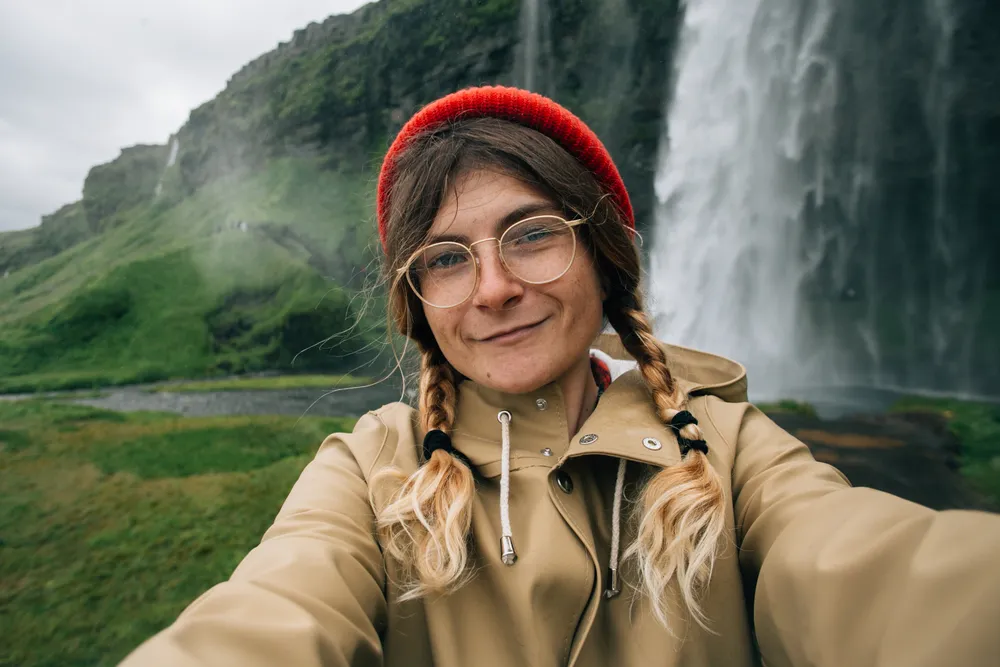 Happy smiling woman make selfie with waterfall