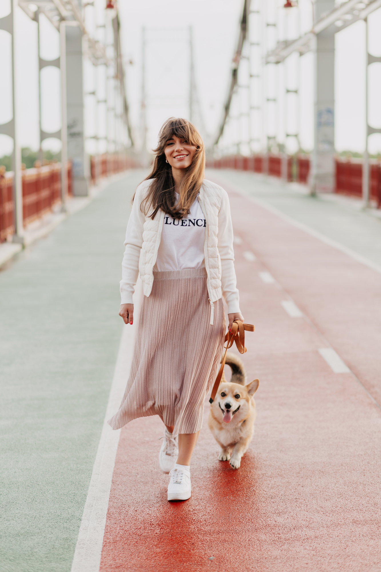 Attractive young woman walking corgi outdoors - stock image