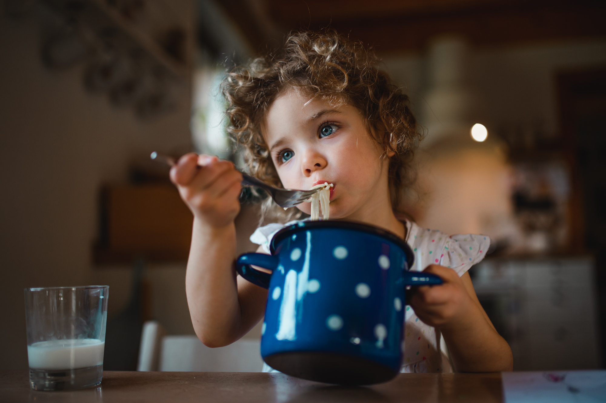 Portrait of sad small girl sitting at table indoors