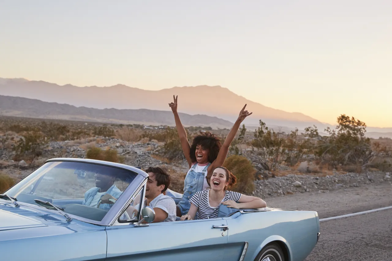 Group Of Friends On Road Trip Driving Classic Convertible Car stock image