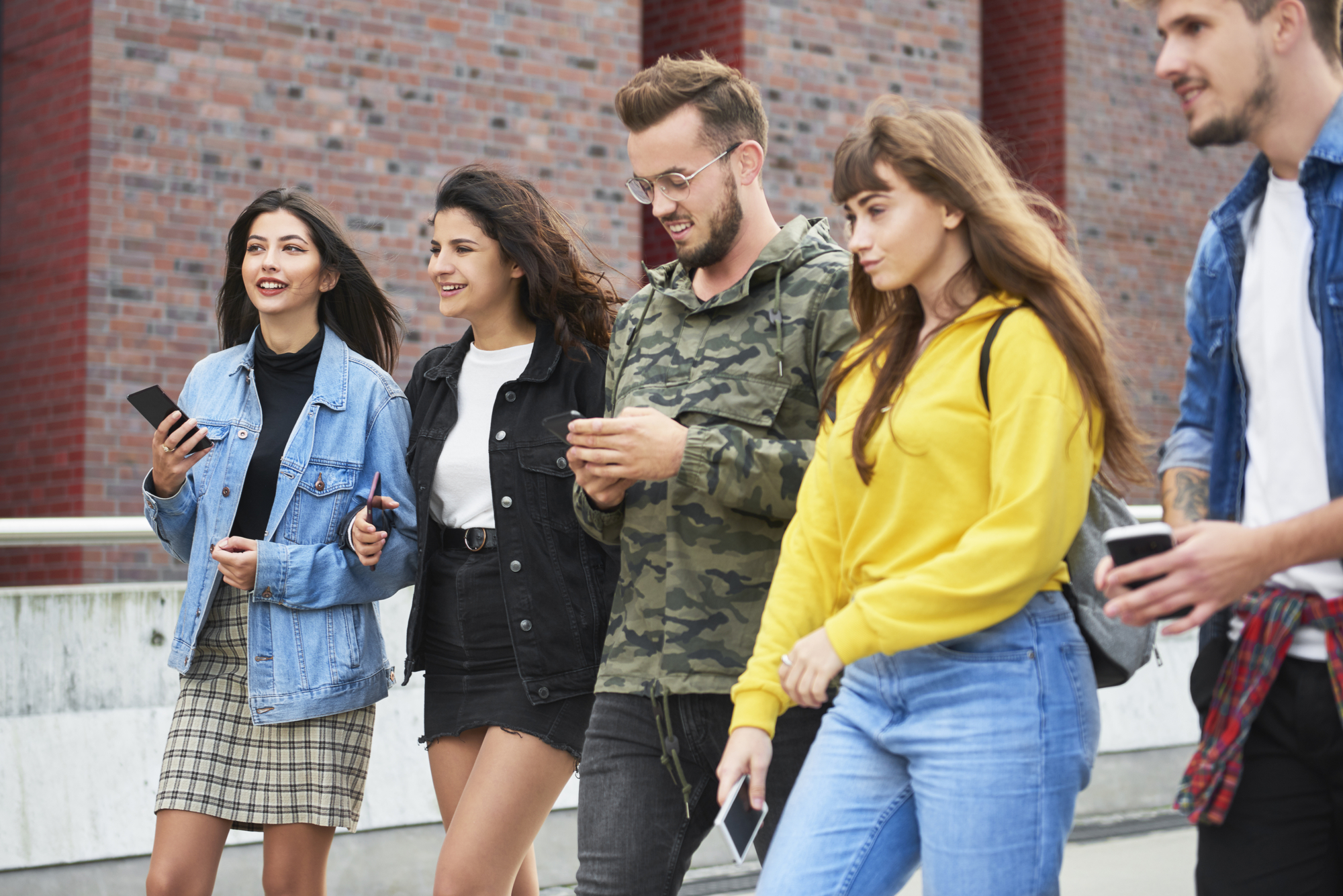 Friends with mobile phones walking city street