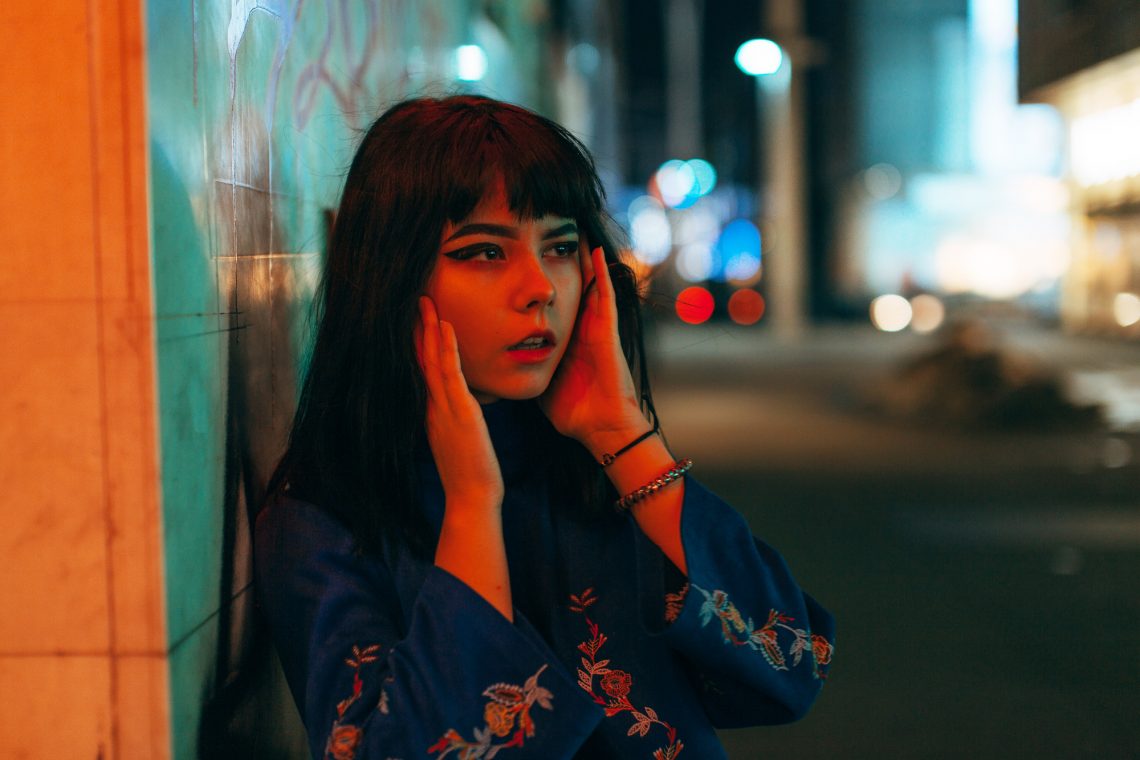 Young Japanese girl stand near neon lights and pose to the camer