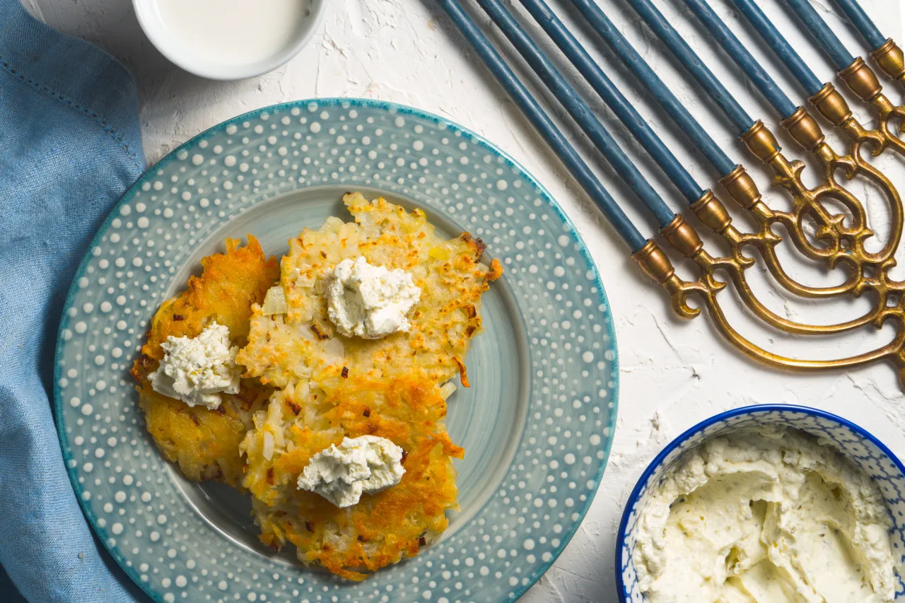 Latkes and curd cheese on a plate and on a blue napkin, chanukia