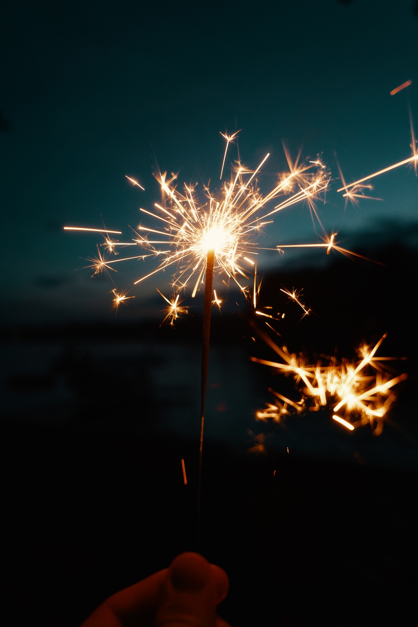 Person holding Bengal lights or sparklers on a dark blurry background