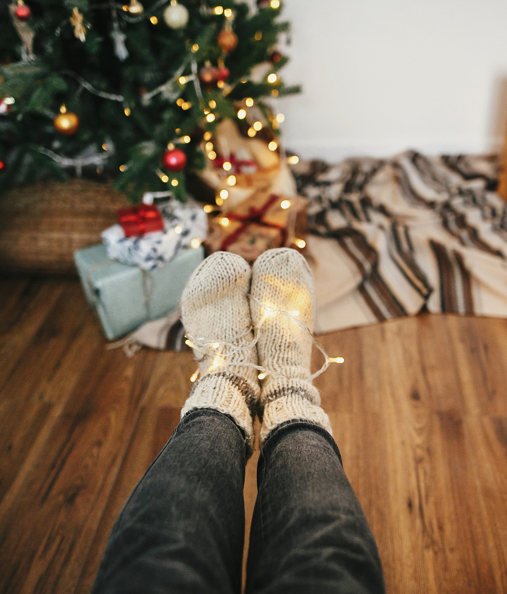 girl legs in stylish warm sock sitting with garland lights at ch