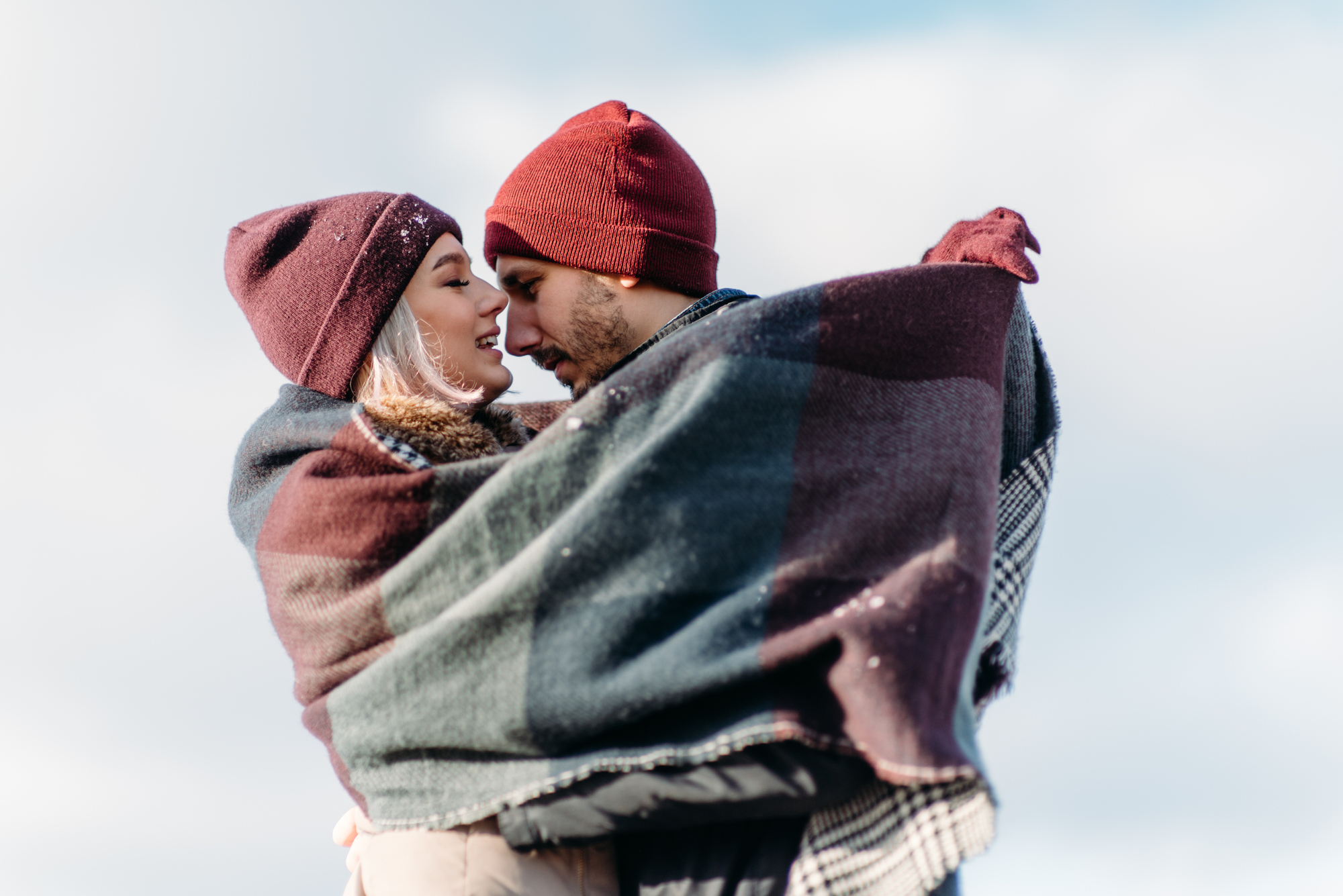 Young hipster couple hugging each other in winter park.