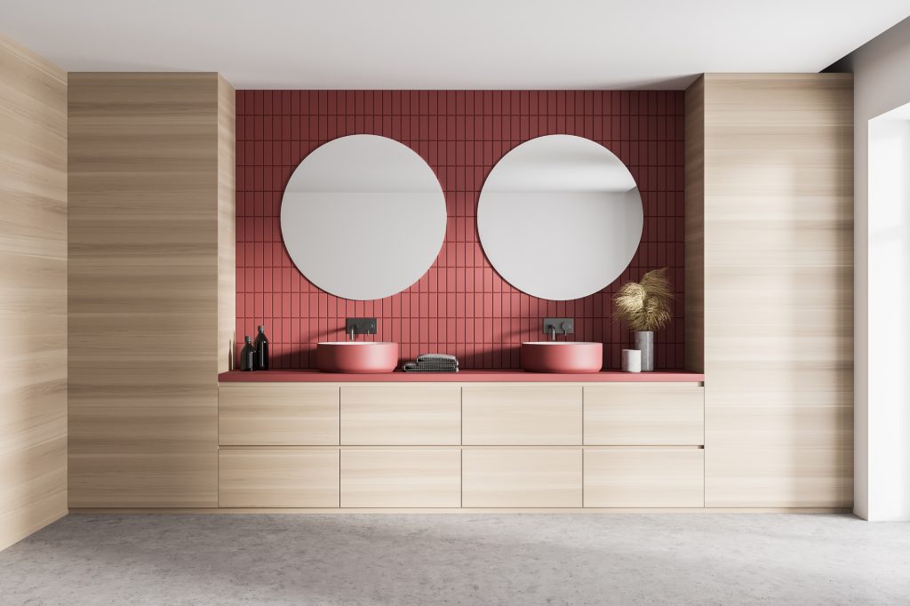 Light wooden bathroom with two red sinks and mirrors, marble floor