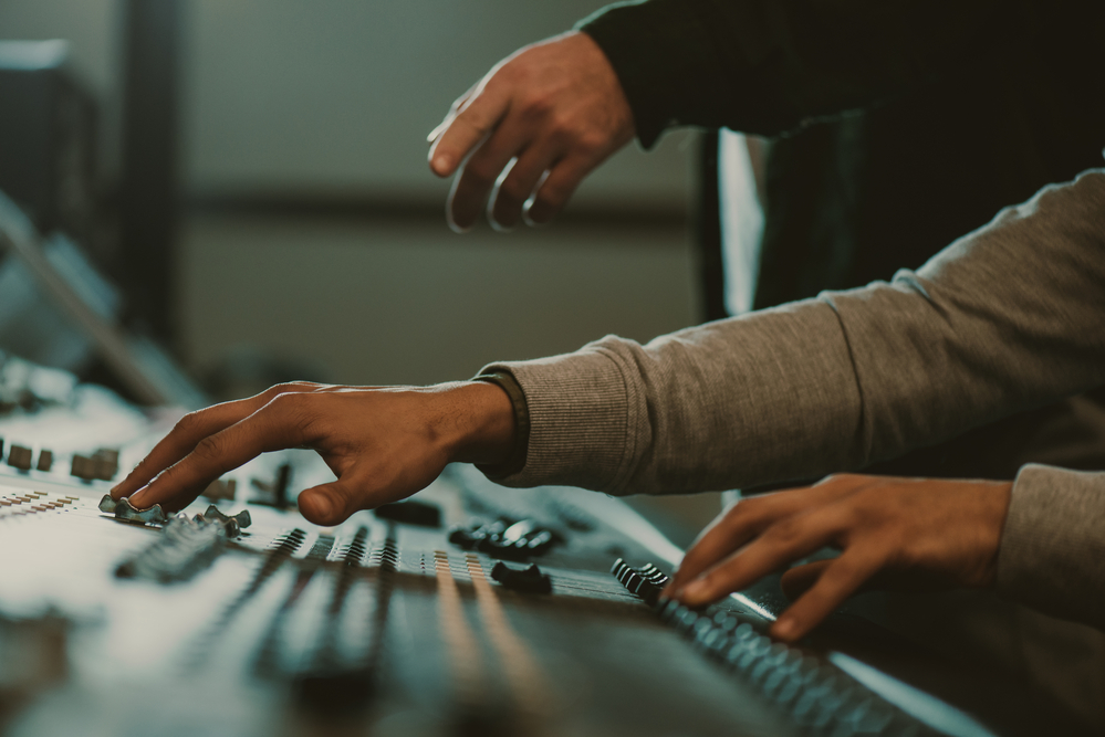 Cropped shot of men using analog graphic equalizer at recording studio