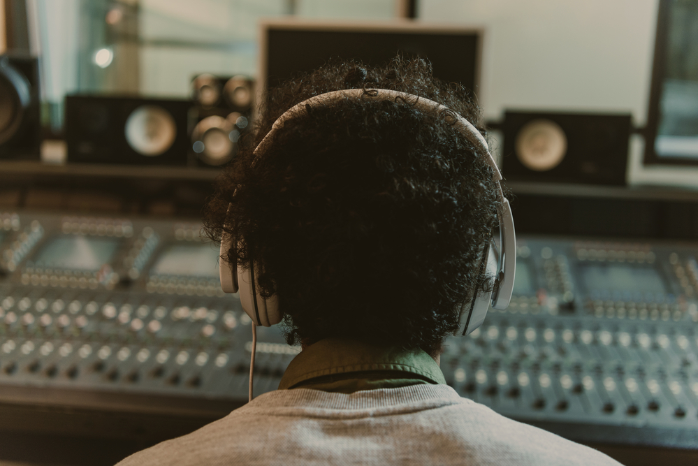 Back view of sound producer in headphones sitting at studio