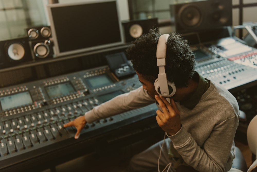 Young sound producer working with analog equalizer at studio