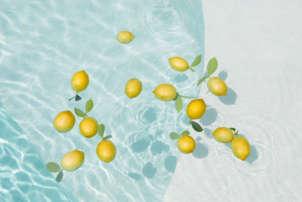 Pool Water With Lemons. Pure Aqua Surface With Glares Pattern And Floating Fresh Citrus.