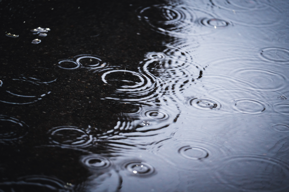 Raindrops in puddle in the city. Defocused photo