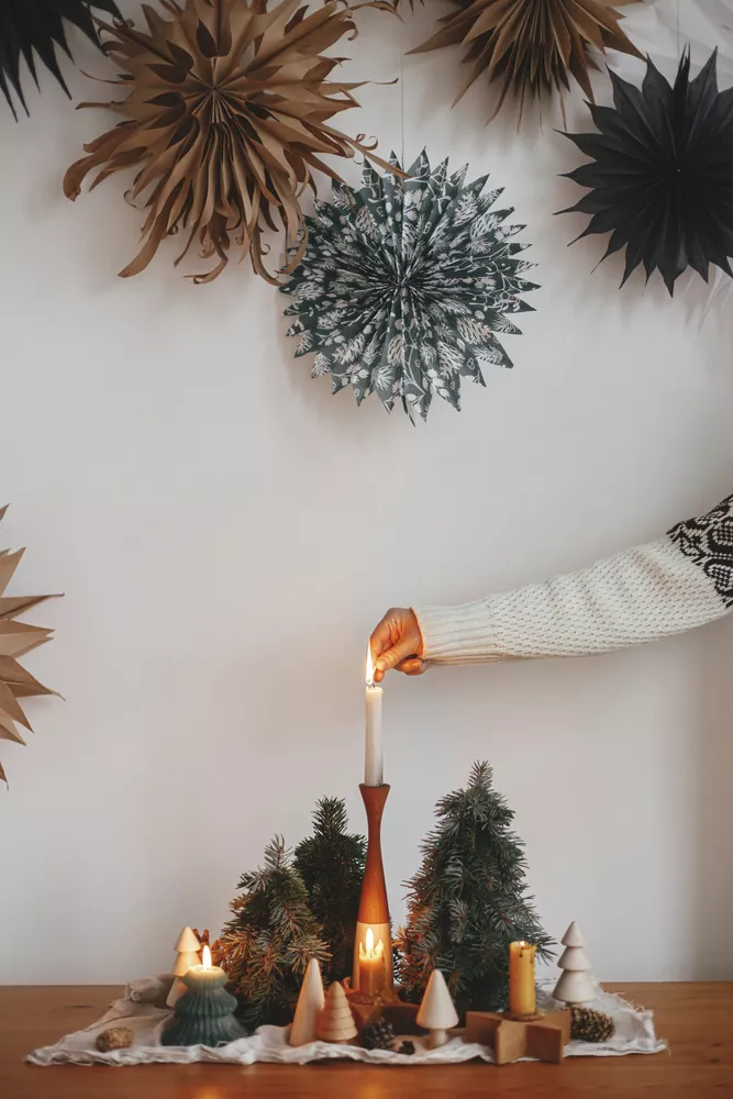 Christmas advent. Hand lighting up christmas candle on table at