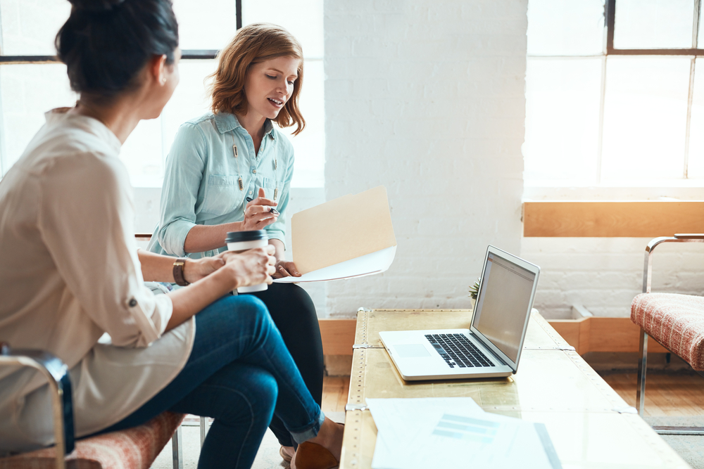 Photo two young businesswomen discussing paperwork in a modern office