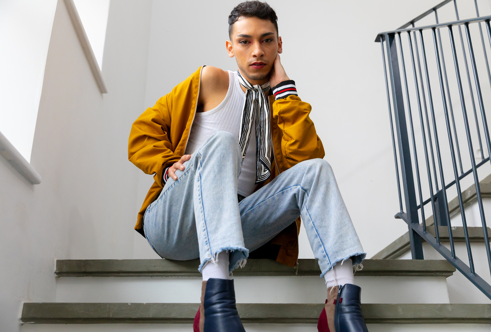 Photo Portrait of biracial transgender man sitting on stairs and looking at camera. 