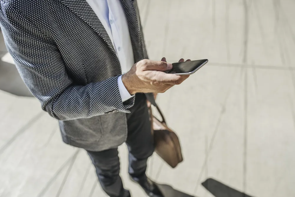 Unrecognisable businessman typing on smartphone.