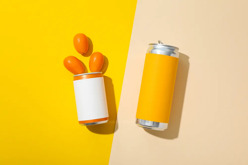 Tin cans and kumquats on yellow background, top view