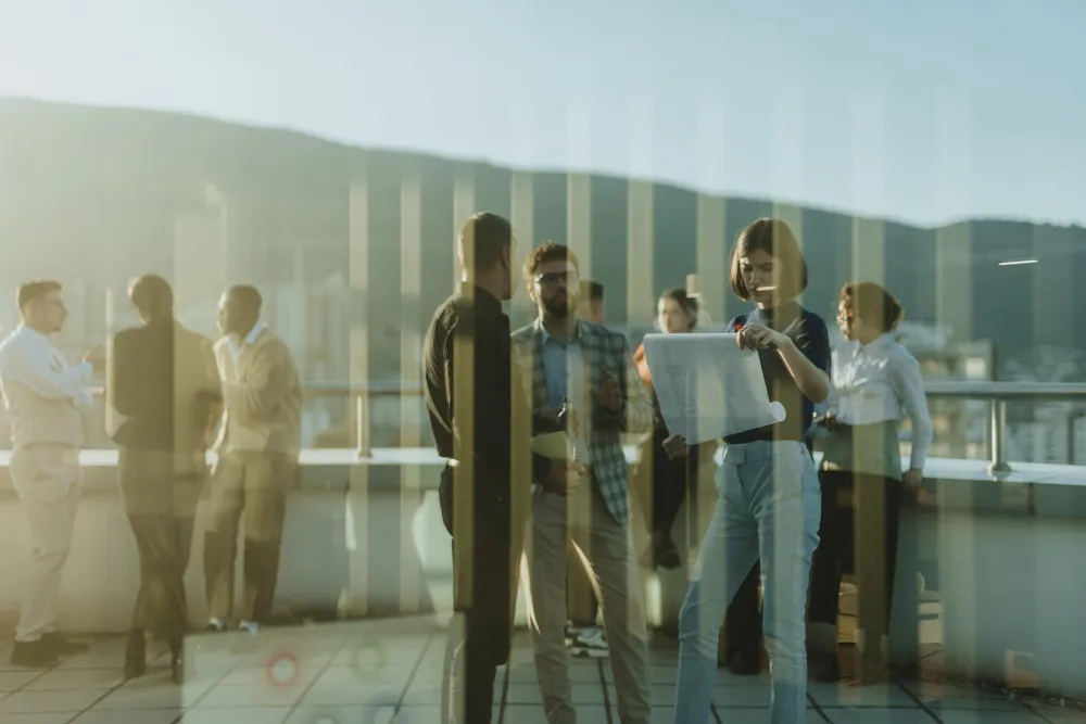 Group of business people standing on a tower balcony, engaged in a brainstorming session. The scene highlights teamwork and innovative thinking with colleagues discussing project solutions against a — Photo 